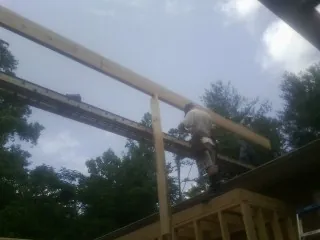 Carpenter setting a ridge beam over a new addition frame — Ice Dam Removal by Roofing Brothers in Doucette