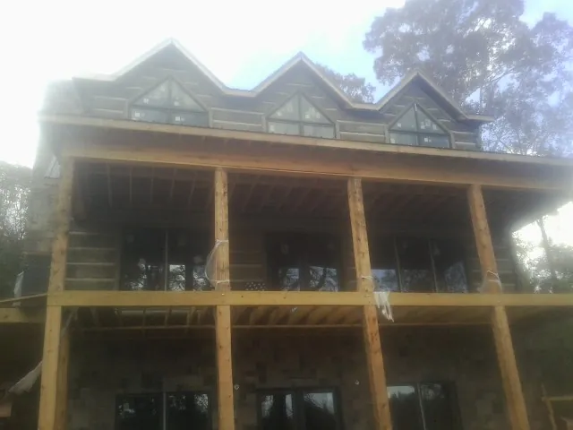 Dormers and porch framing on a large log home under construction — Roof Coating work by our crew in Doucette