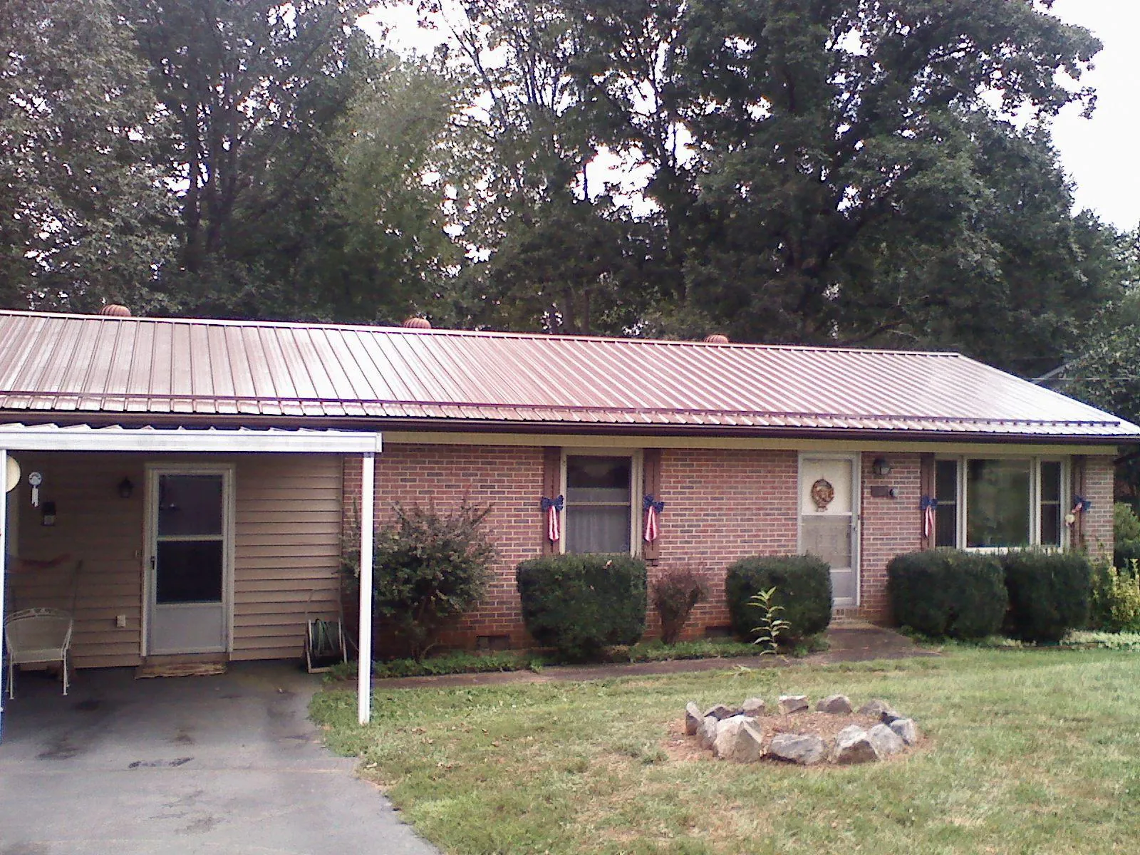 Bronze metal roof and carport on a brick ranch home — Roof Repair work by our crew in Doucette