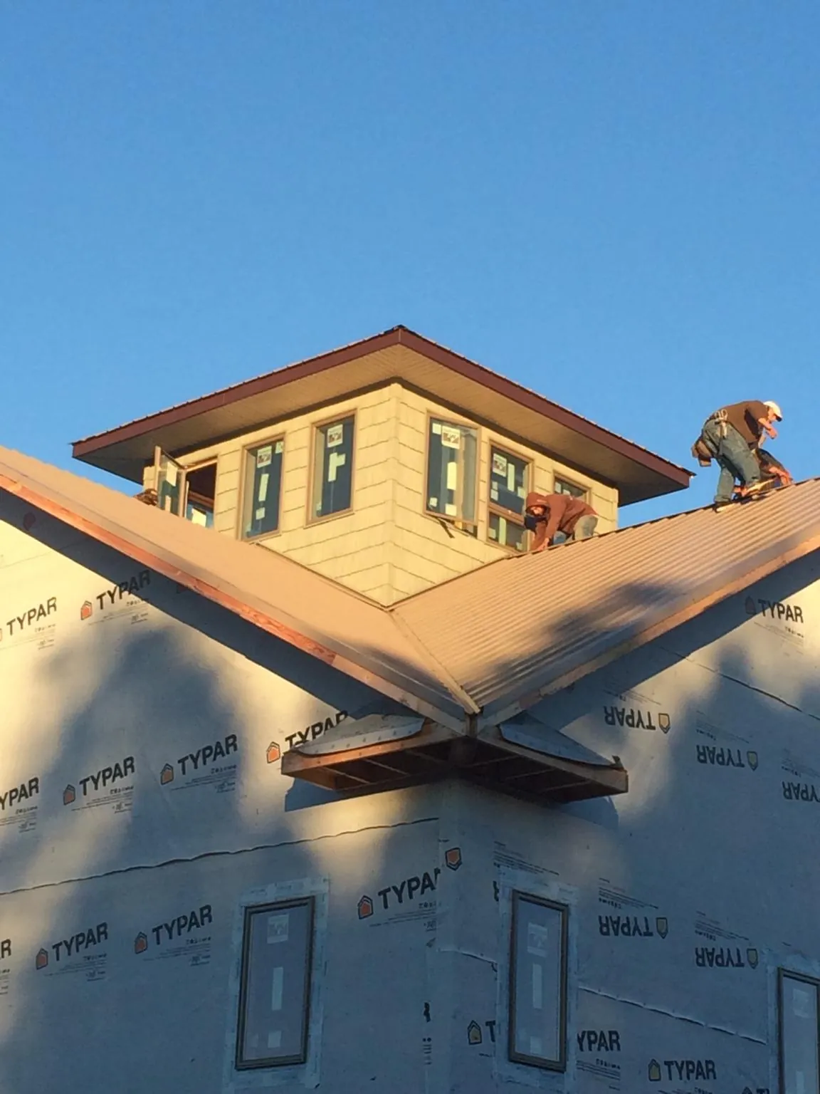 Roofers working around a rooftop cupola on a new metal roof at sunset — Roof Waterproofing in Doucette by Roofing Brothers